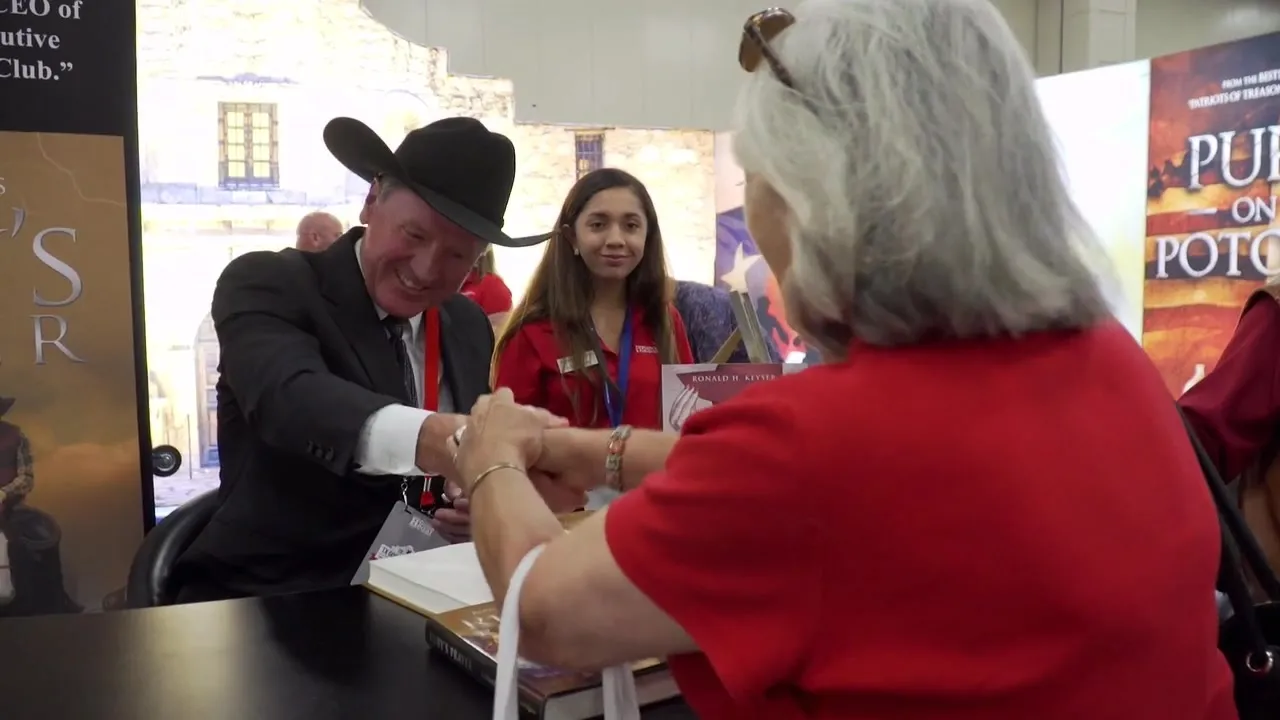 An author in a black hat signing a book for a reader
