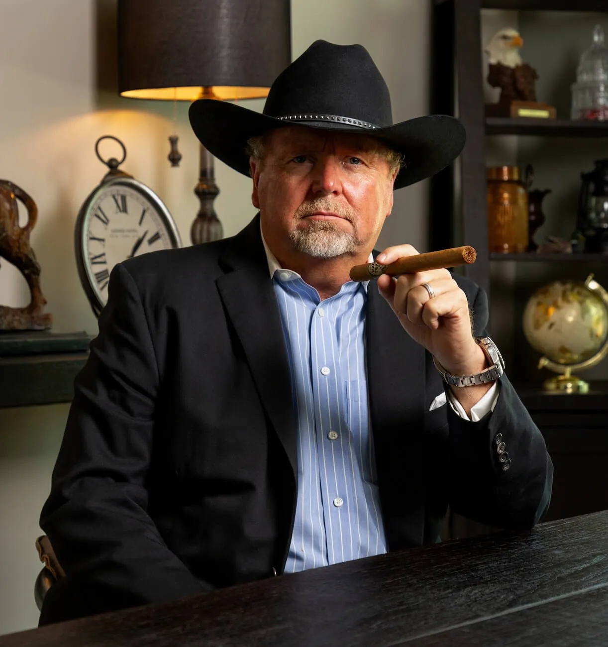 David Thomas Roberts seated at a desk in a black hat and jacket